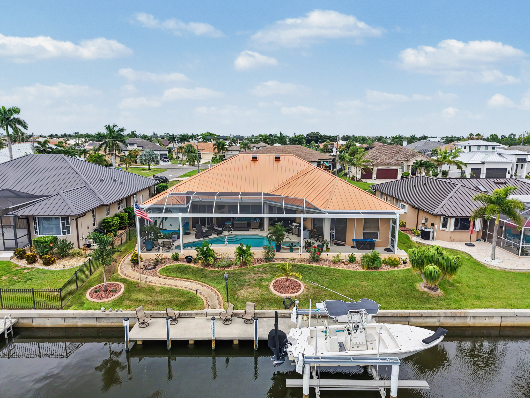 Rear aerial view of a waterfront residence showing a copper metal roof, screened pool enclosure, lan 