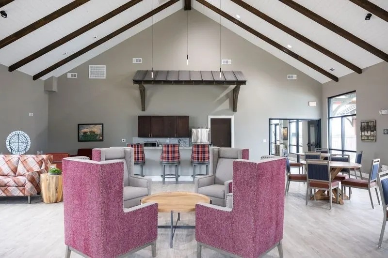 A room with a pink chair in the foreground and a couch in the background.