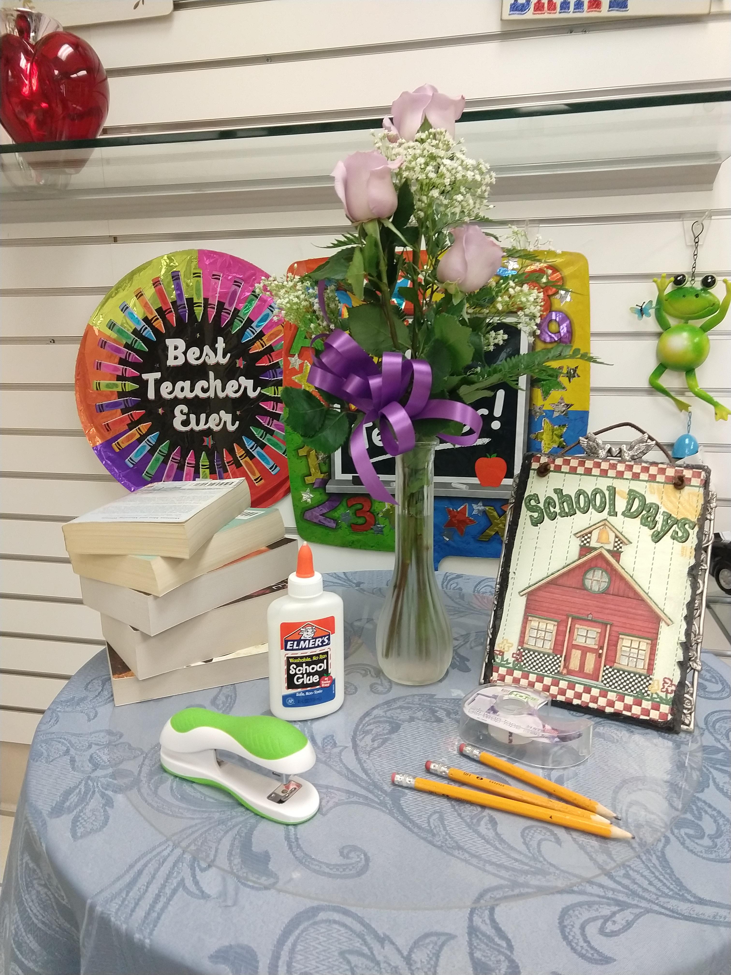 Fort Bragg Flower Shop back to school display table with a budvase of fresh lavender roses accented with asters and a purple bow.