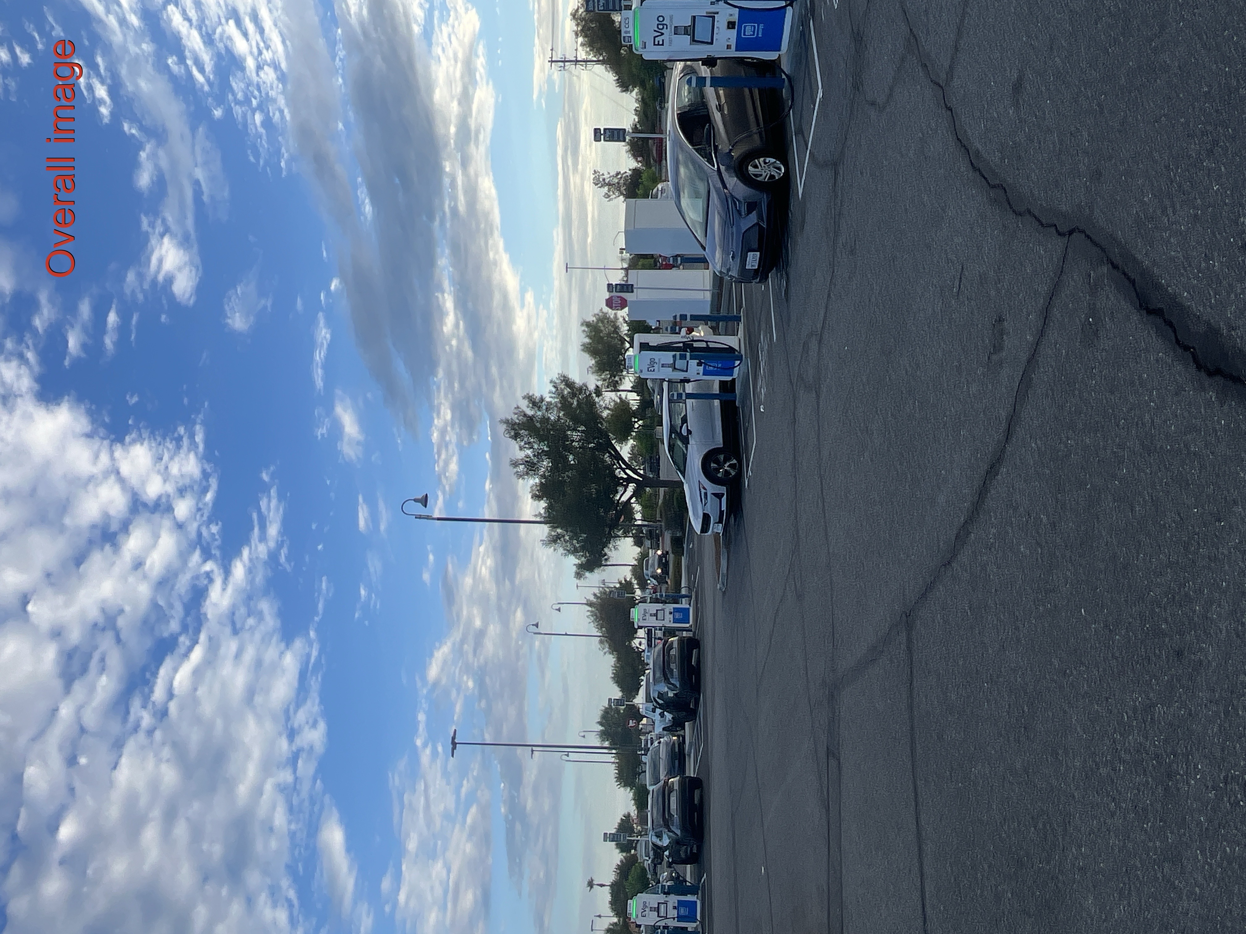 Several EVgo fast charging units installed in marked parking spaces at a public charging station, wi 