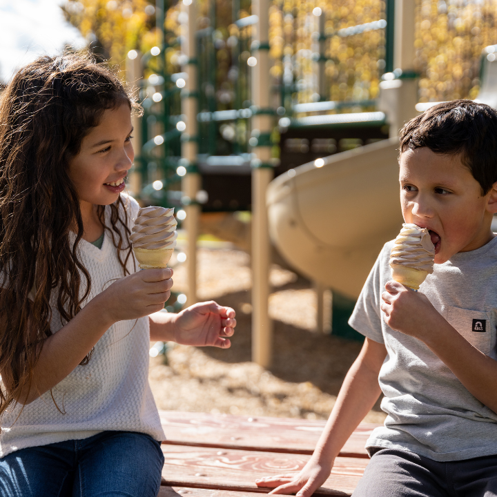 Two children enjoying soft serve ice cream outside of Little America's playground.