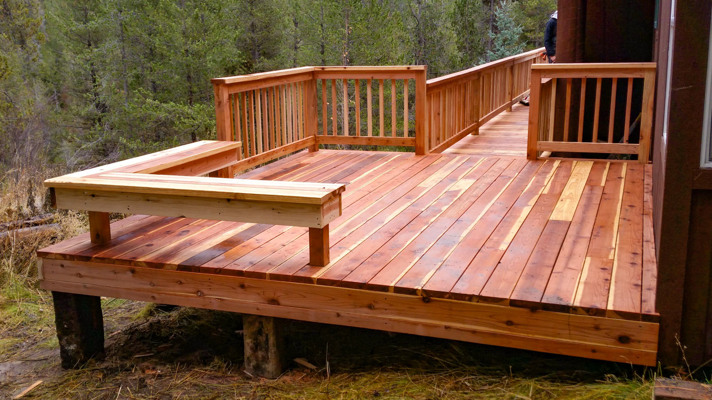 Experience the timeless beauty of natural wood with this custom raised deck by DeckPro LLC. Designed to blend seamlessly into the wooded surroundings, this project features rich wood tones, a sturdy built-in bench for seating, and a convenient long walkway ramp for easy access.