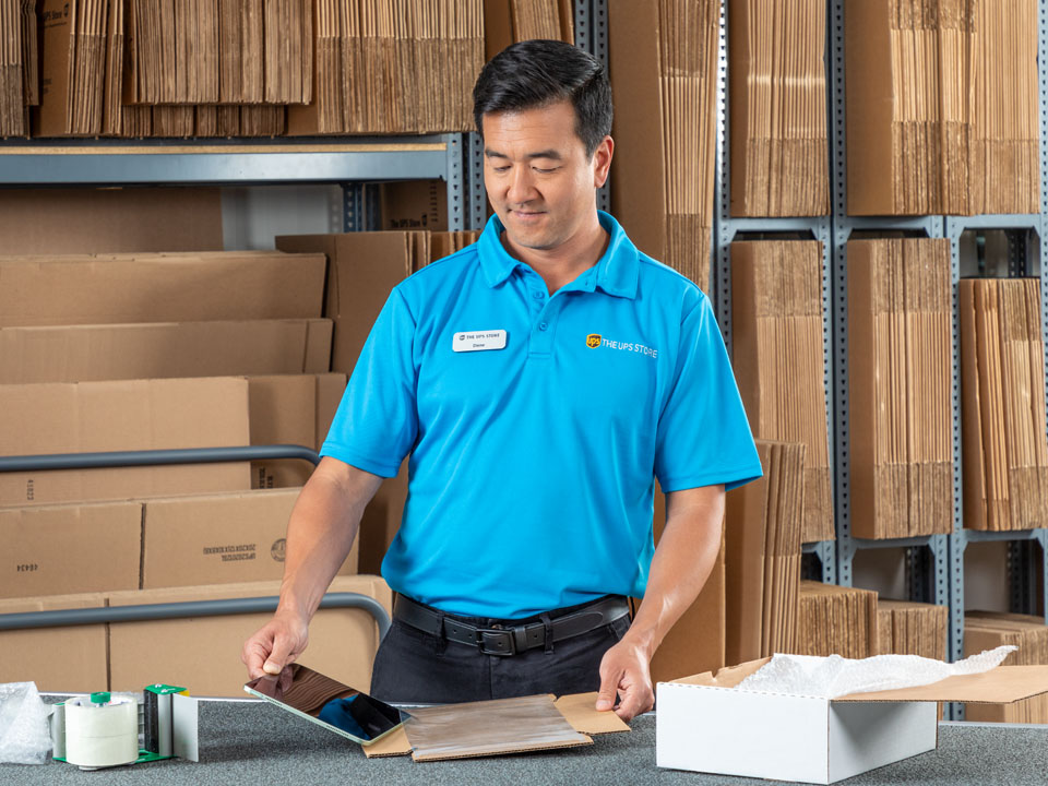 A UPS Store employee packing up an ipad for shipping