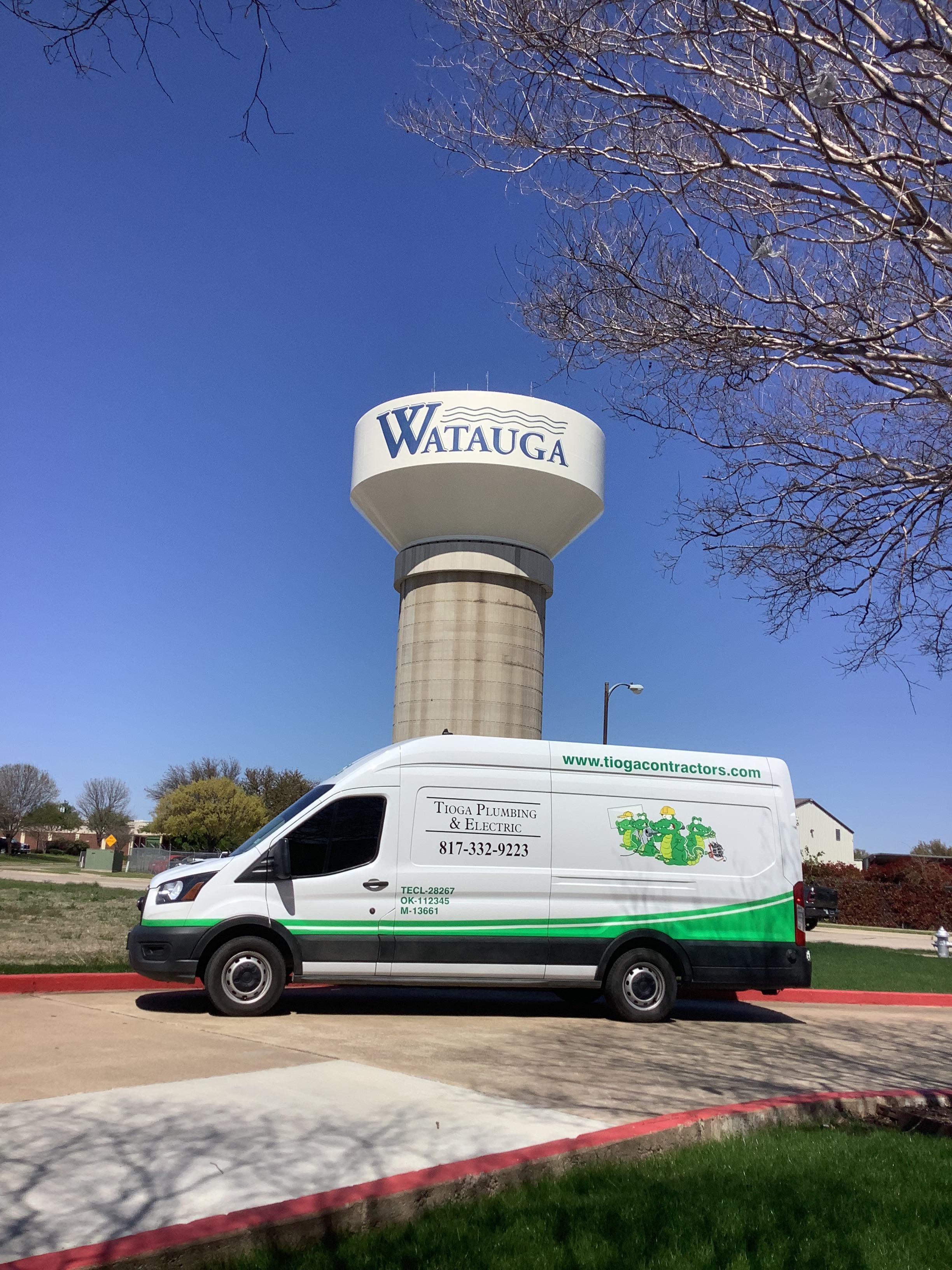 A Tioga Plumbing & Electric service van in front of one of the Watauga Texas water towers.