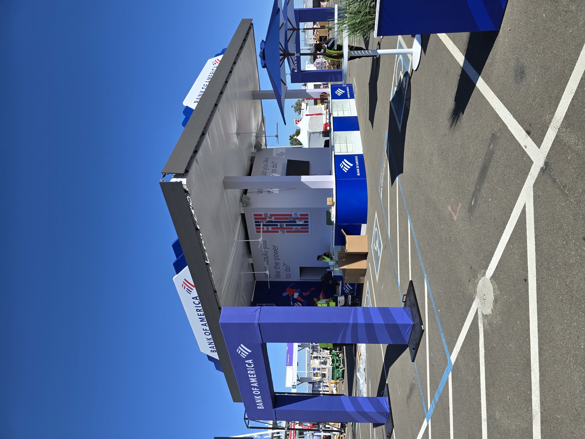 Wide view of the custom Bank of America outdoor activation featuring a branded pavilion, entrance arch, display counters, and event furnishings.