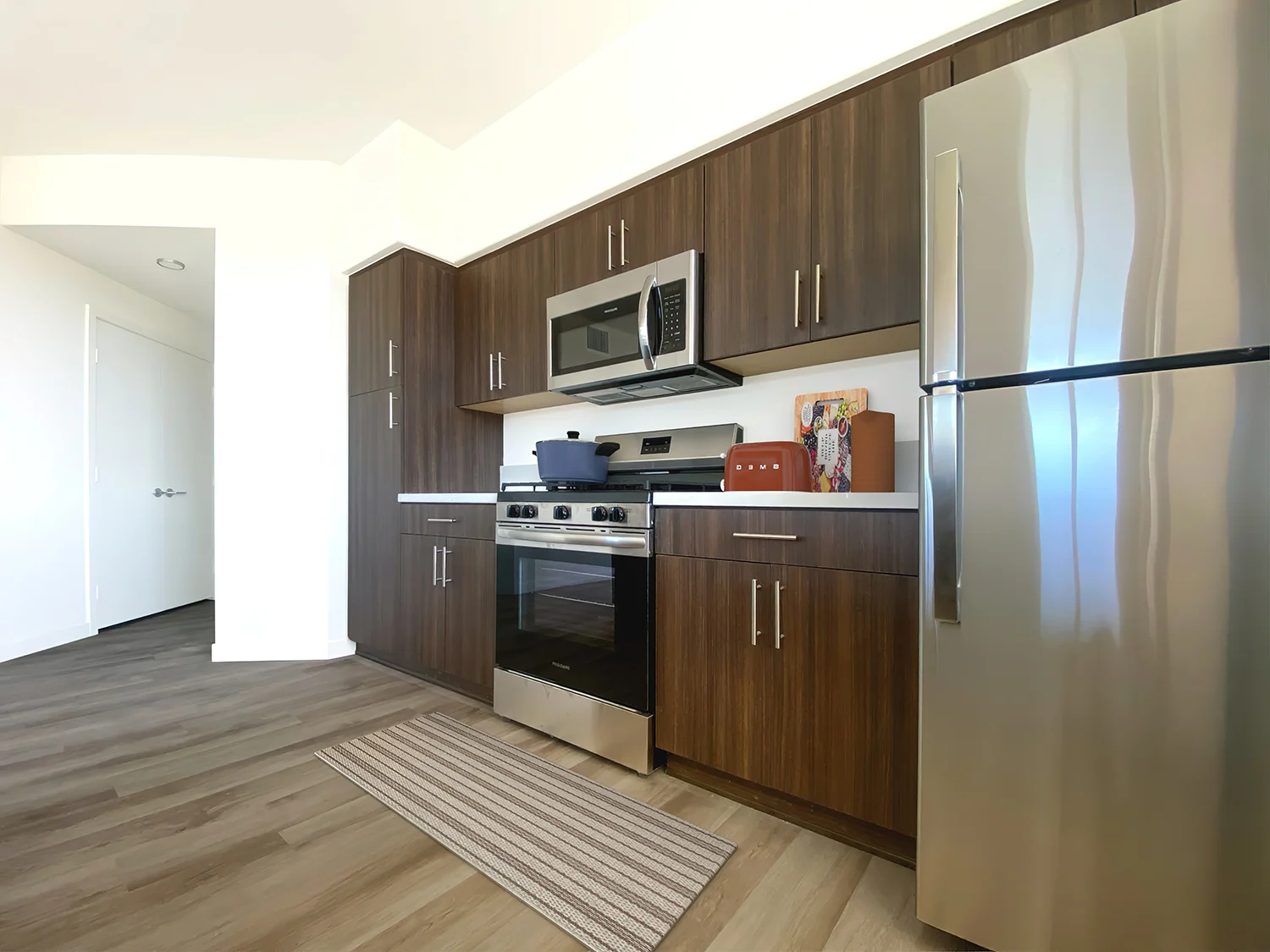 A modern kitchen with a stainless steel refrigerator.at The Park on Washington, Murrieta California 