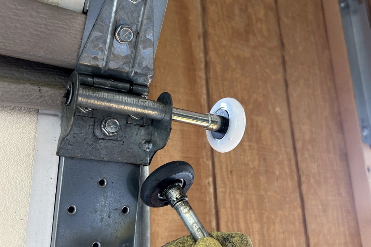 Old garage door roller compared with a new nylon roller during Garage Fixer roller replacement servi 