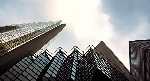 Street view looking up to tall buildings that stand against a cloudy sky.