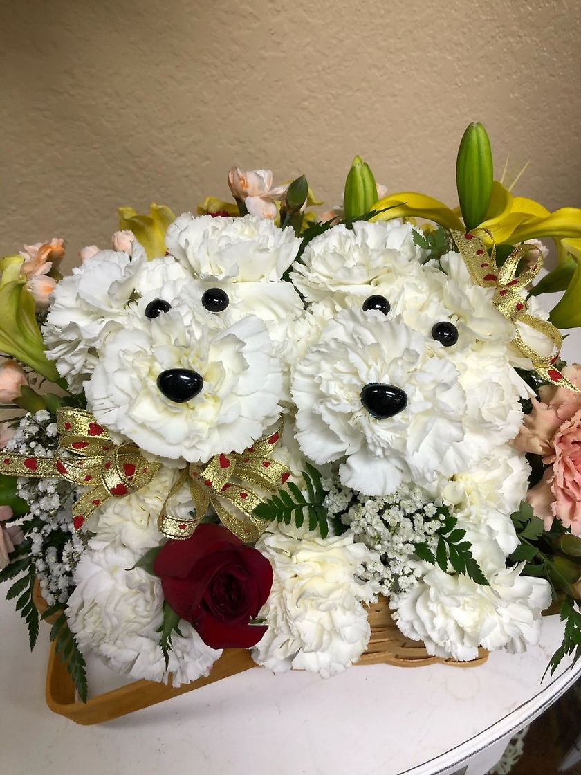 Our Cute Couple - What's more adorable than a puppy made out of Carnations? TWO Puppies made out of Carnations! Our Cute Couple is set in a cute wicker basket with sweet-scented Baby's Breath, Lilies and Carnations, and each puppy is adorned with a ribbon.