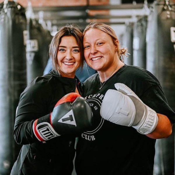 Women posing with TITLE Boxing Club gloves at their local TITLE Boxing Club gym.