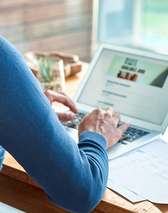 Close-up of a person working on their laptop at a desk.