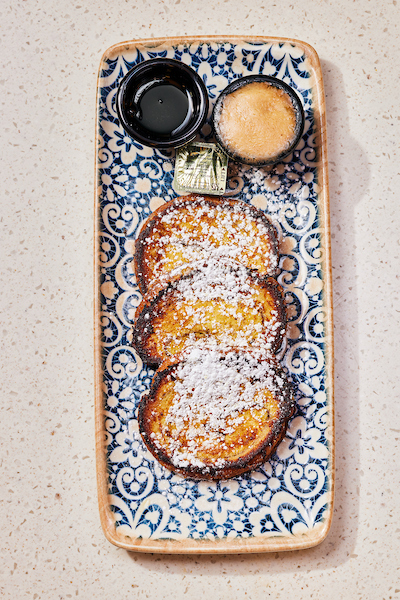 Baguette French Toast, dusted with powdered sugar and a side of whipped cinnamon butter and maple sy 