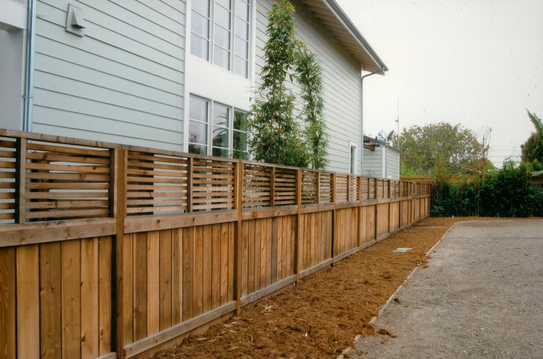 Horizontal wood fence installation beside a residential home, offering privacy with a modern fencing style.