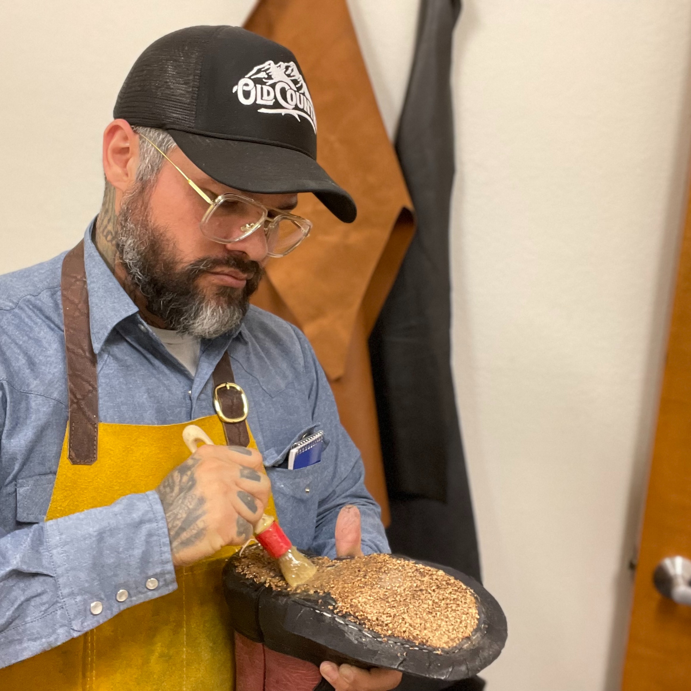 An Old Country bootmaker applies materials to the bottom of a cowboy boot during the construction pr 