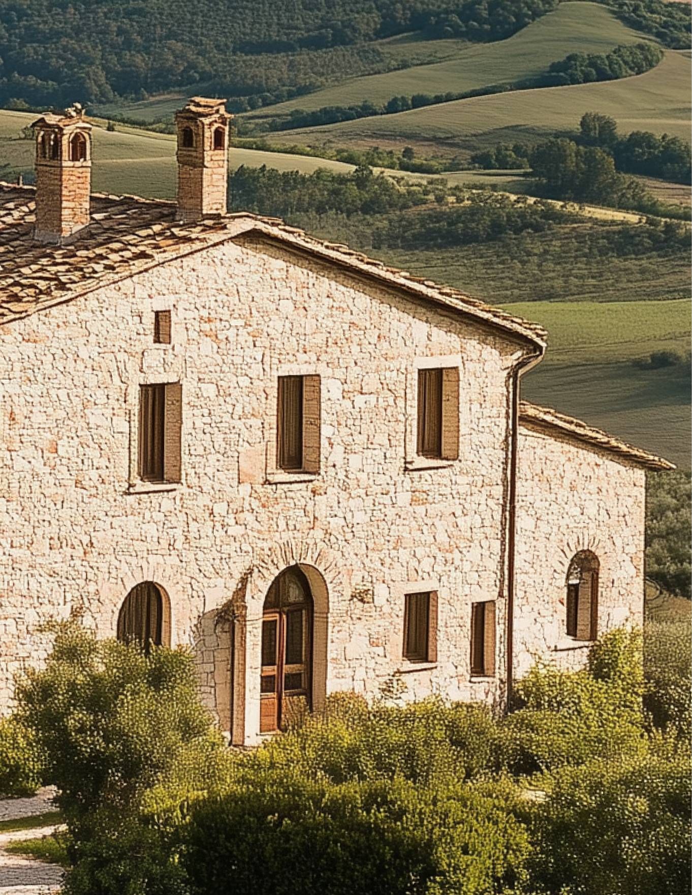 Rustic countryside stone house with traditional architecture, arched windows, tiled roof, and scenic rolling hills backdrop, reflecting timeless construction style and natural integration within rural landscape.