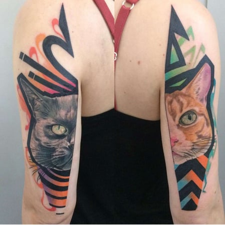 Eisenherz Tattoo und Piercing Magdeburg - Katzen Portrait Tattoos an beiden Oberarmen mit kräftigen Farben, grafischen Formen und markanten Kontrasten. Individuelle Cat Tattoos für Keywords wie Katzen Tattoo, Color Tattoo, Portrait Tattoo, Oberarm T...