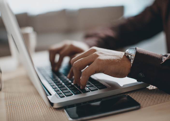 Close-up of a person typing on their laptop.