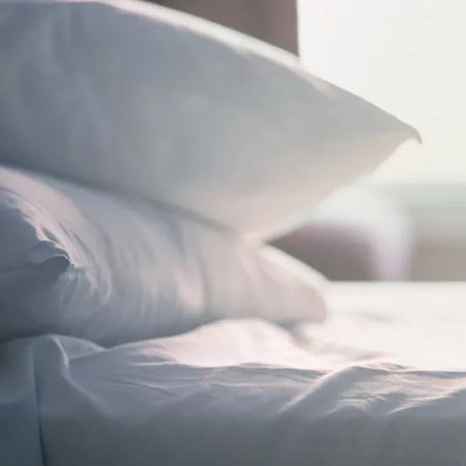 Deux oreillers sont posés sur des draps blancs impeccables dans un hôtel Premier Inn.