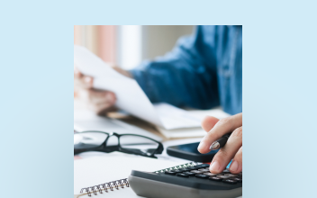 Gros plan d’une personne qui examine ses documents fiscaux avec une calculatrice.