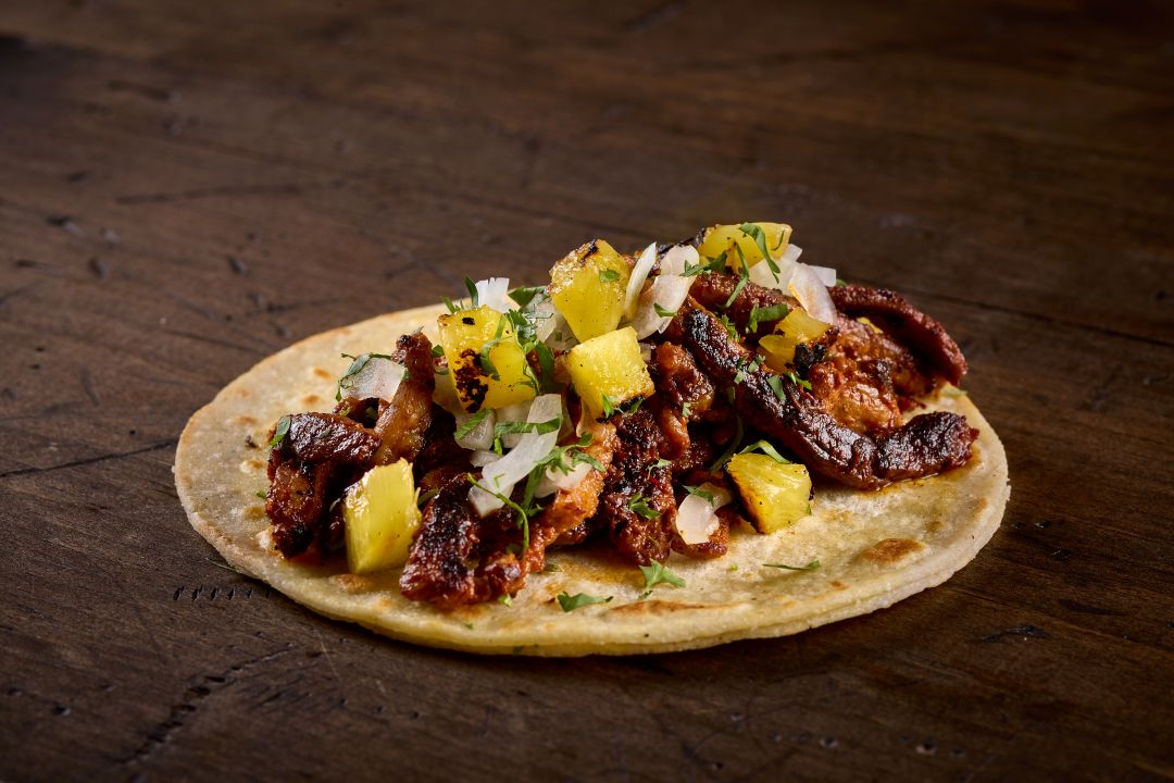 Spiced Pork and Pineapple, al pastor taco served on corn tortillas and topped with sliced onions and cilantro found on the menu at Taco Bamba