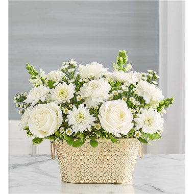 Celebrate the life of a loved one with our beautiful floral tribute. A mix of all-white blooms is a symbol of enduring love. Designed in our Remembrance Cachepot, featuring an embossed pattern and finished with a gold brushed ivory surface.