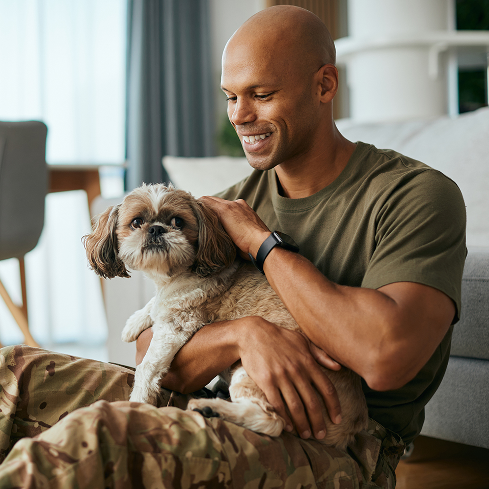 A man in military apparel holding a dog