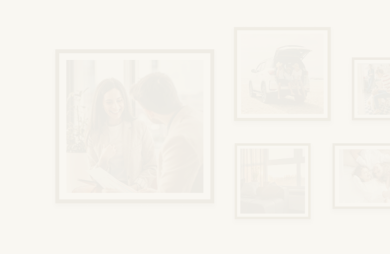 A gallery wall featuring framed photos of a couple and their dog, a mom and daughter smiling together, a family on a beach vacation, and an advisor meeting with a client.