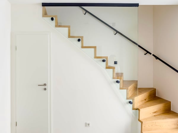 Moderne Treppenverglasung aus Sicherheitsglas mit Punkthaltern und schwarzem Deckenprofil für klare Linien.