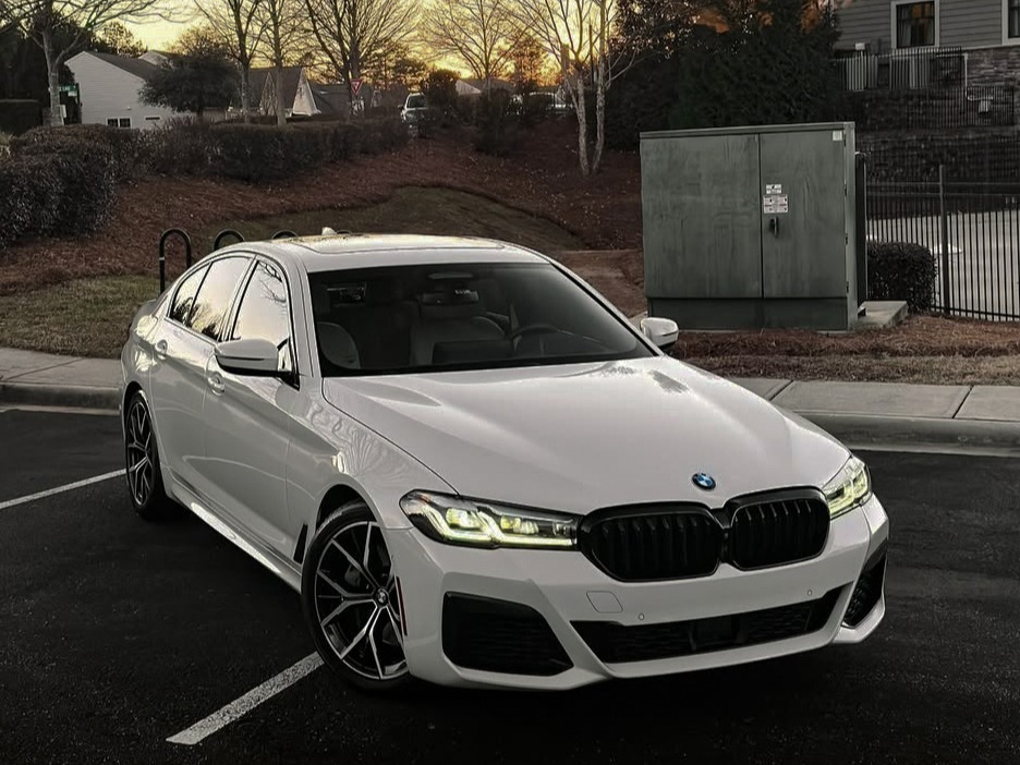 Pristine white BMW 5 Series sedan gleaming after professional auto detailing service, parked outdoors.