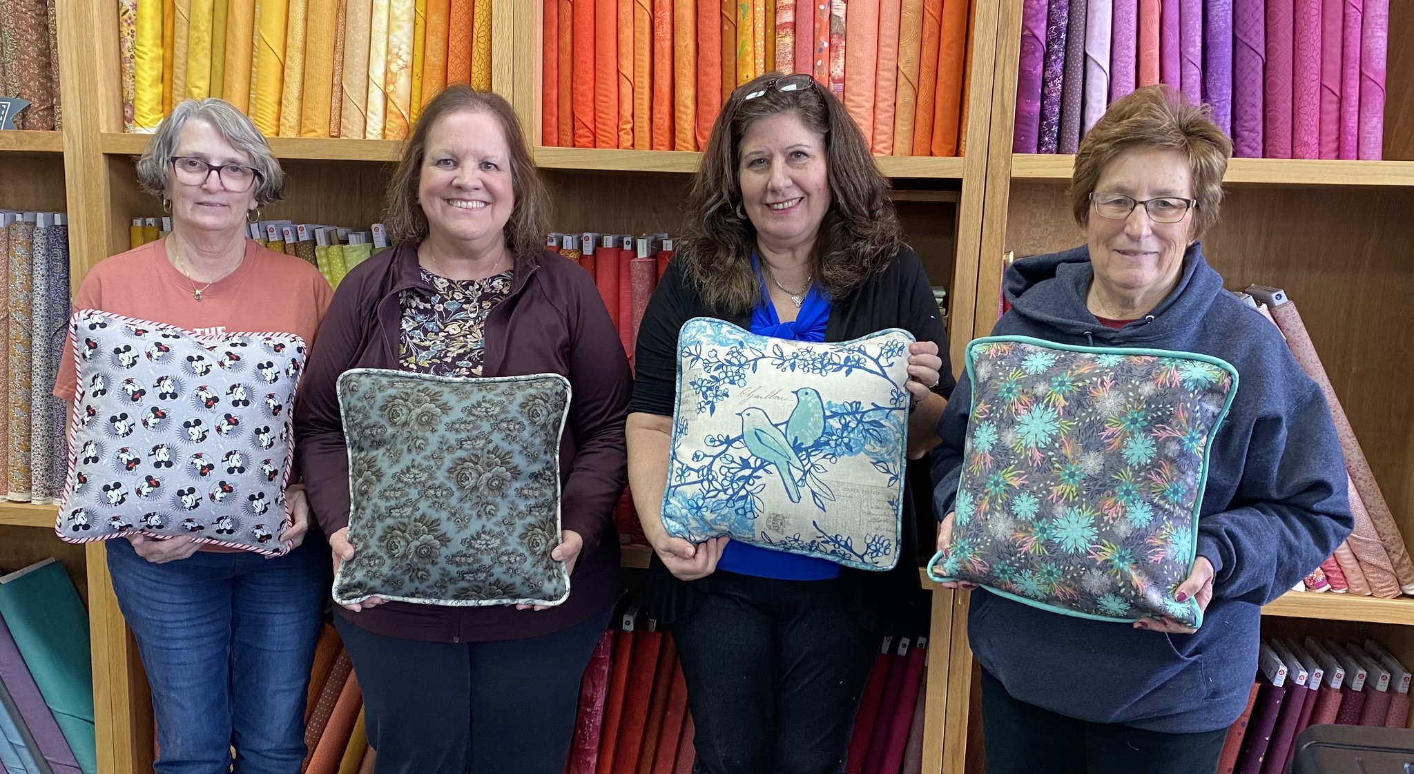 Students proudly display their finished custom throw pillows after a Decorative Stitch class. This hands-on sewing workshop featured decorative stitching, piping techniques, and personalized home décor projects.