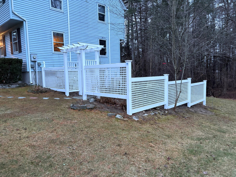 This project features 4-foot white vinyl fencing with full lattice panels, offering an elegant, semi-open boundary that complements the surrounding landscape
