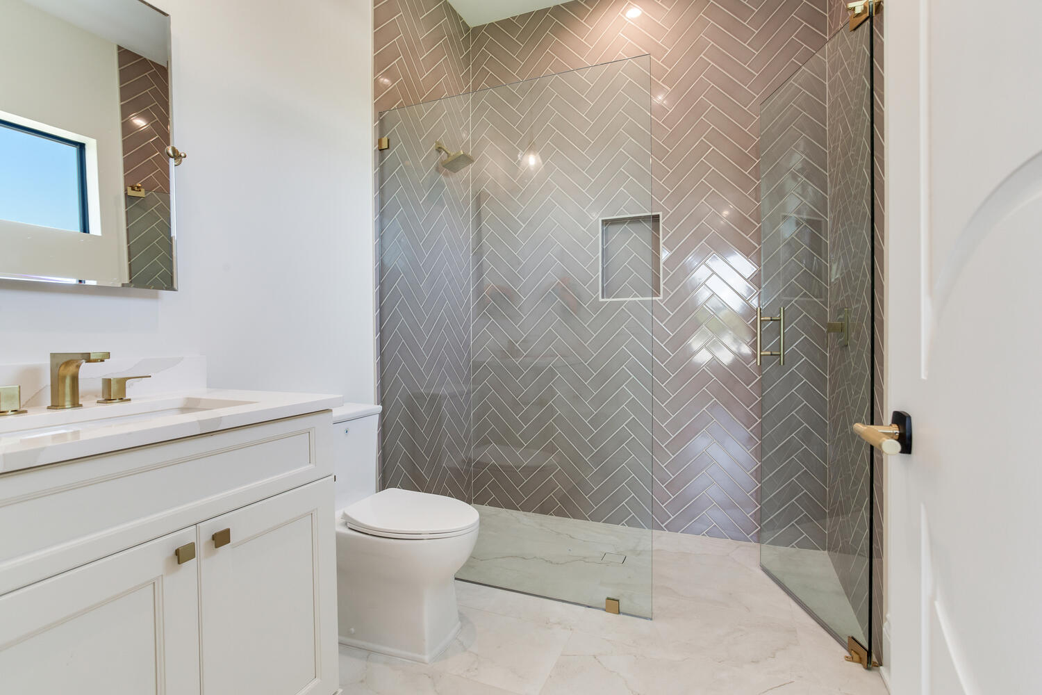 Modern luxury bathroom with a glass-enclosed walk-in shower, light vanity, marble-look tile, and clean contemporary finishes.