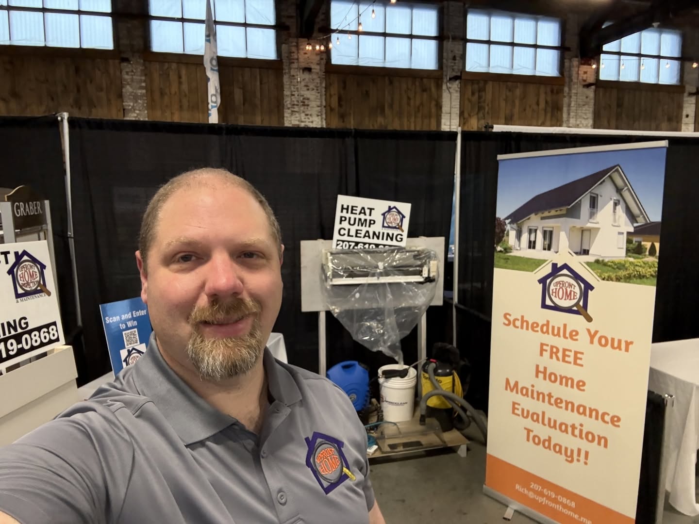 Rick Browning, owner of Upfront Home Inspection & Maintenance, representing his company at a home improvement event in Maine. The display highlights Upfront's heat pump cleaning, home inspection, and preventative home maintenance services.