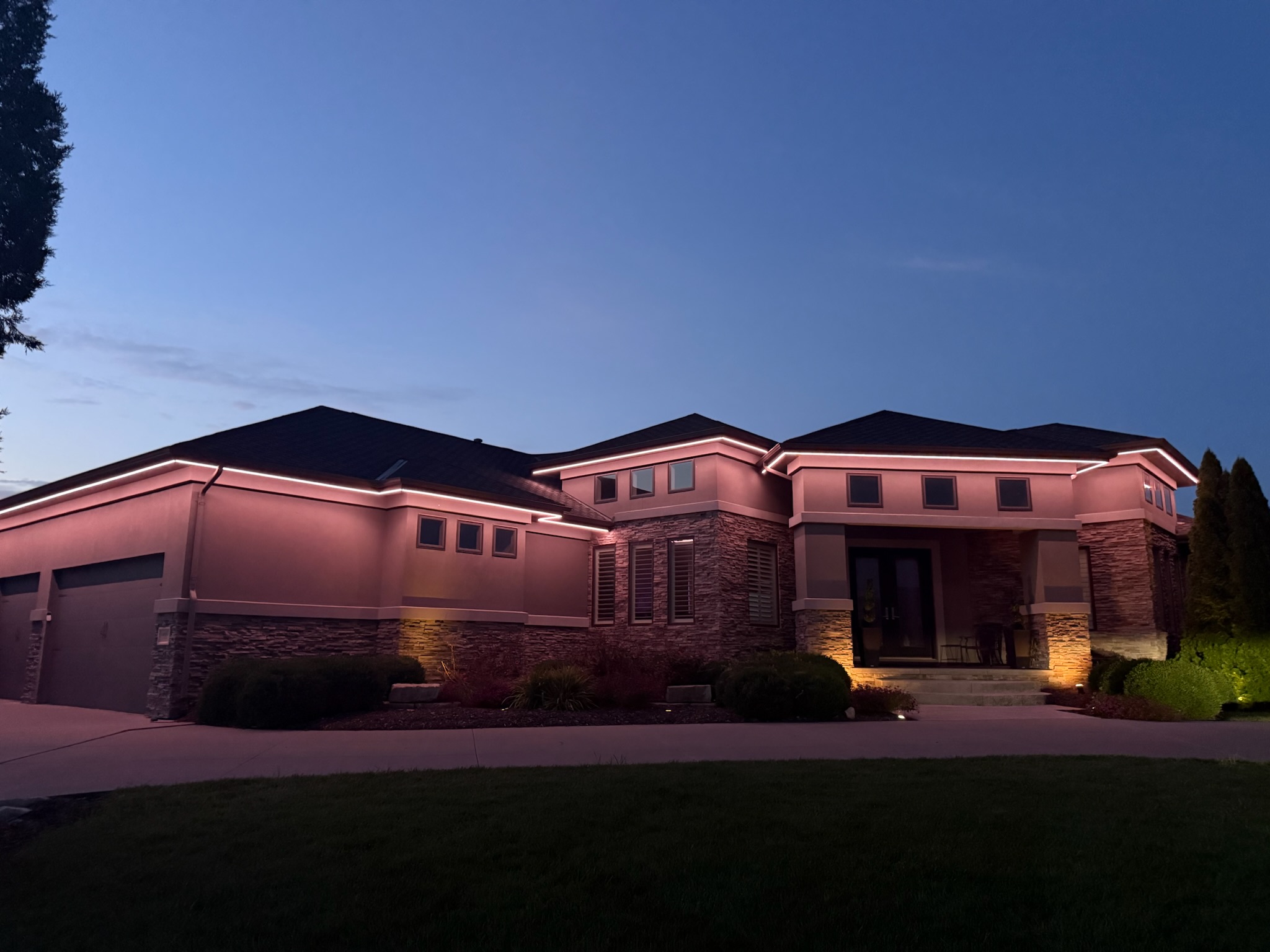 Warm exterior accent lighting illuminating the roofline and facade of a large residential property.