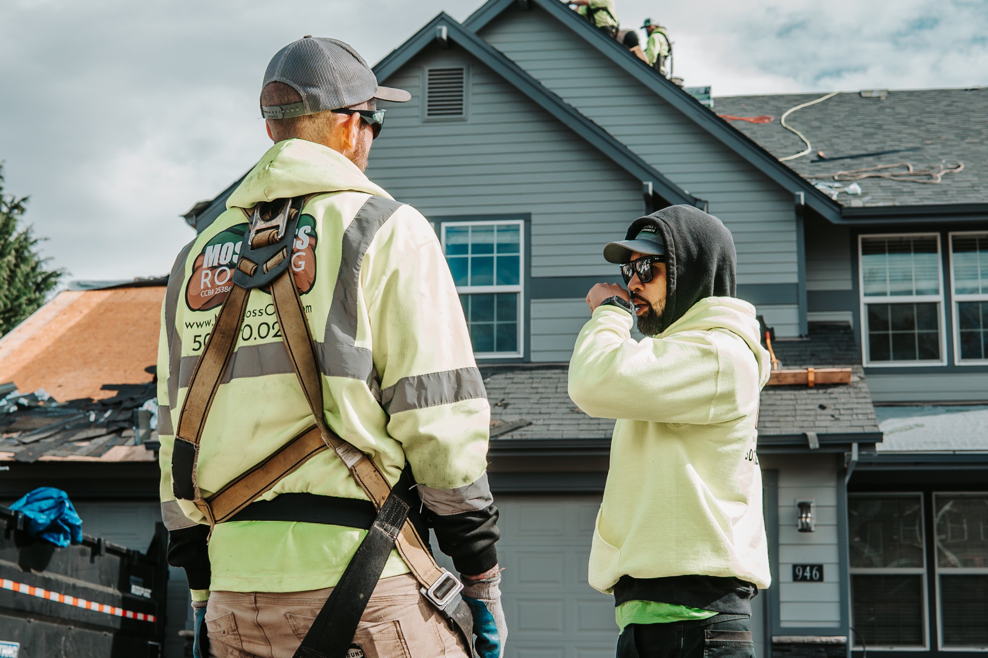 Roofing professional discussing a residential roofing project with co-worker. 