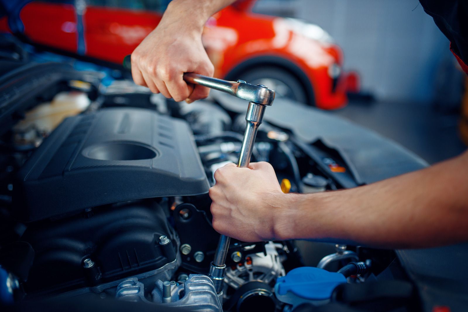 Close-up of hands using a ratchet wrench to tighten or loosen engine components. The image highlights precision mechanical work, focusing on automotive repair tasks that ensure engine performance, reliability, and proper maintenance in a workshop setting.