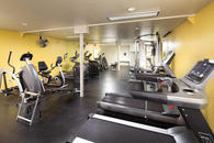 Fitness center with weight machines, cardio machines, and fan.