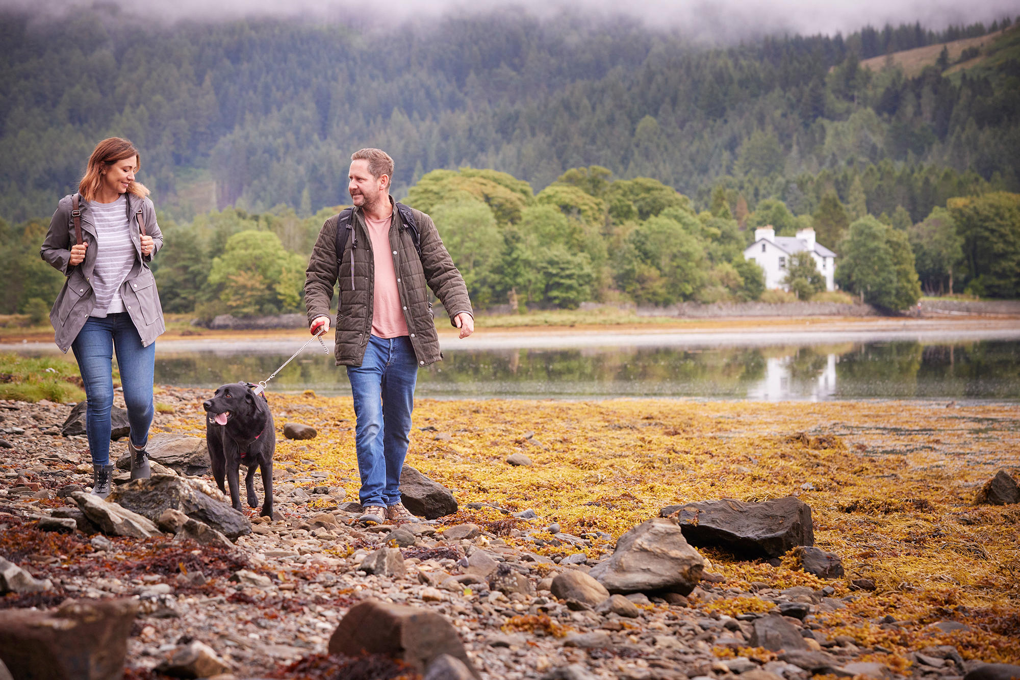 Couple stroll with their dog through the grounds of Drimsynie Estate