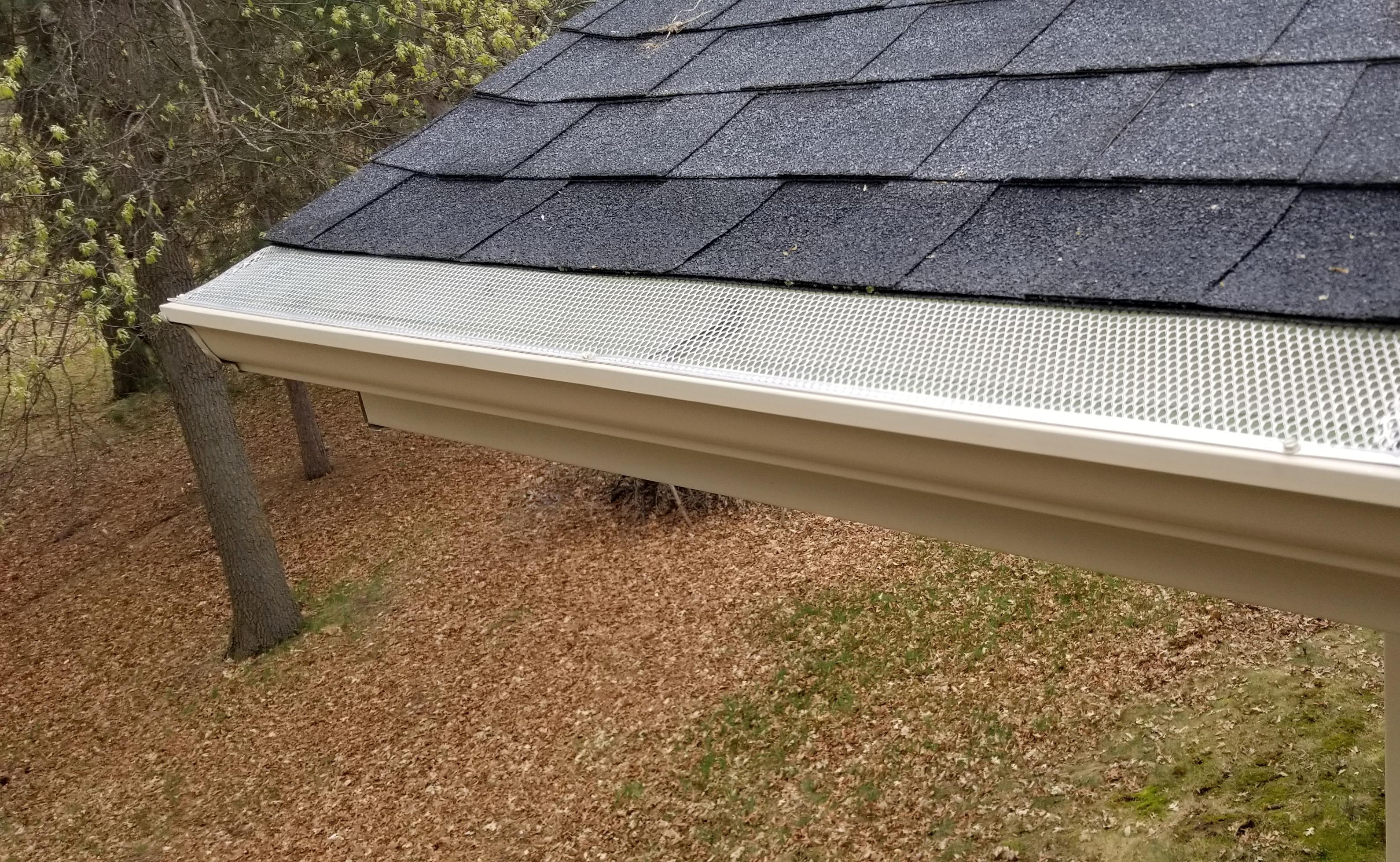 Close-up of a seamless gutter with a protective metal mesh gutter guard installed on a roof by Ultimate Gutter Solutions.