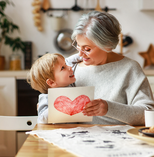 A grandmother and her grandchild drawing together at the kitchen table.