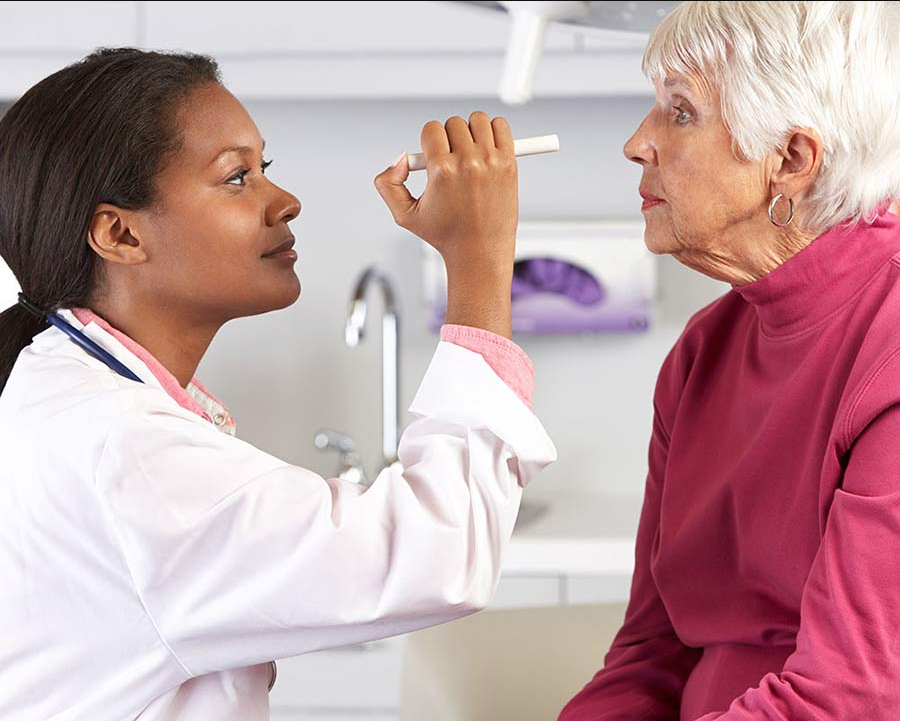 Optometrist using a penlight on a senior patient