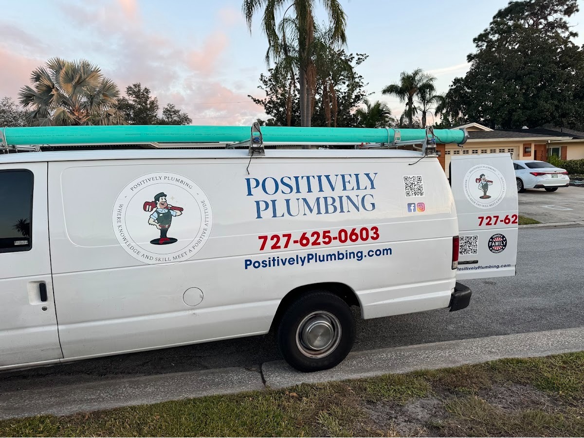 Positively Plumbing service van parked outside, featuring the company logo, phone number, and branding for professional plumbing services.