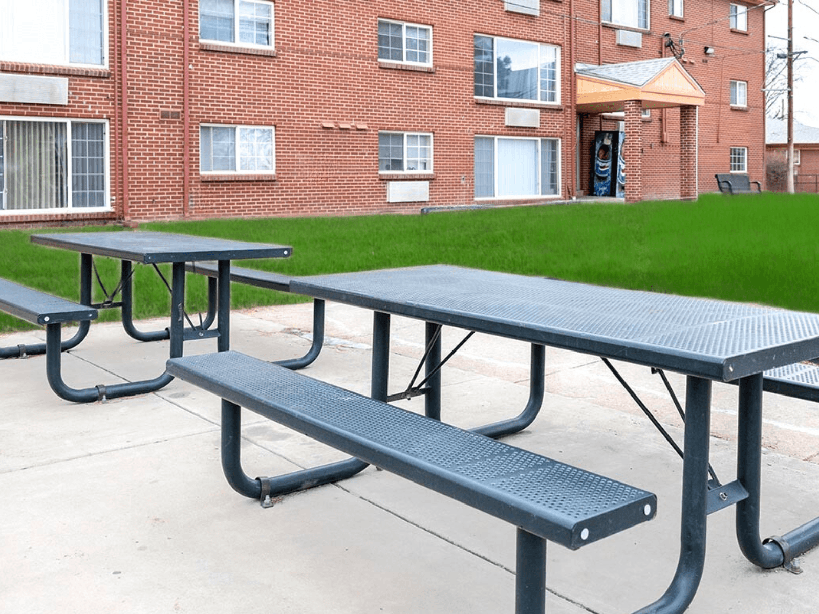 A black picnic table and bench in front of a brick building