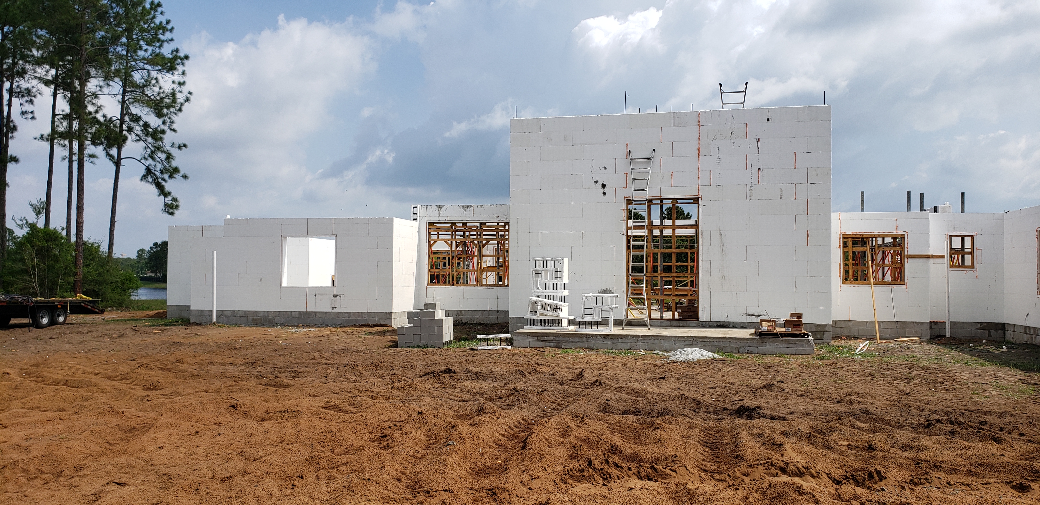 A house under construction is shown. The walls are made of white foam blocks, and wooden frames for  