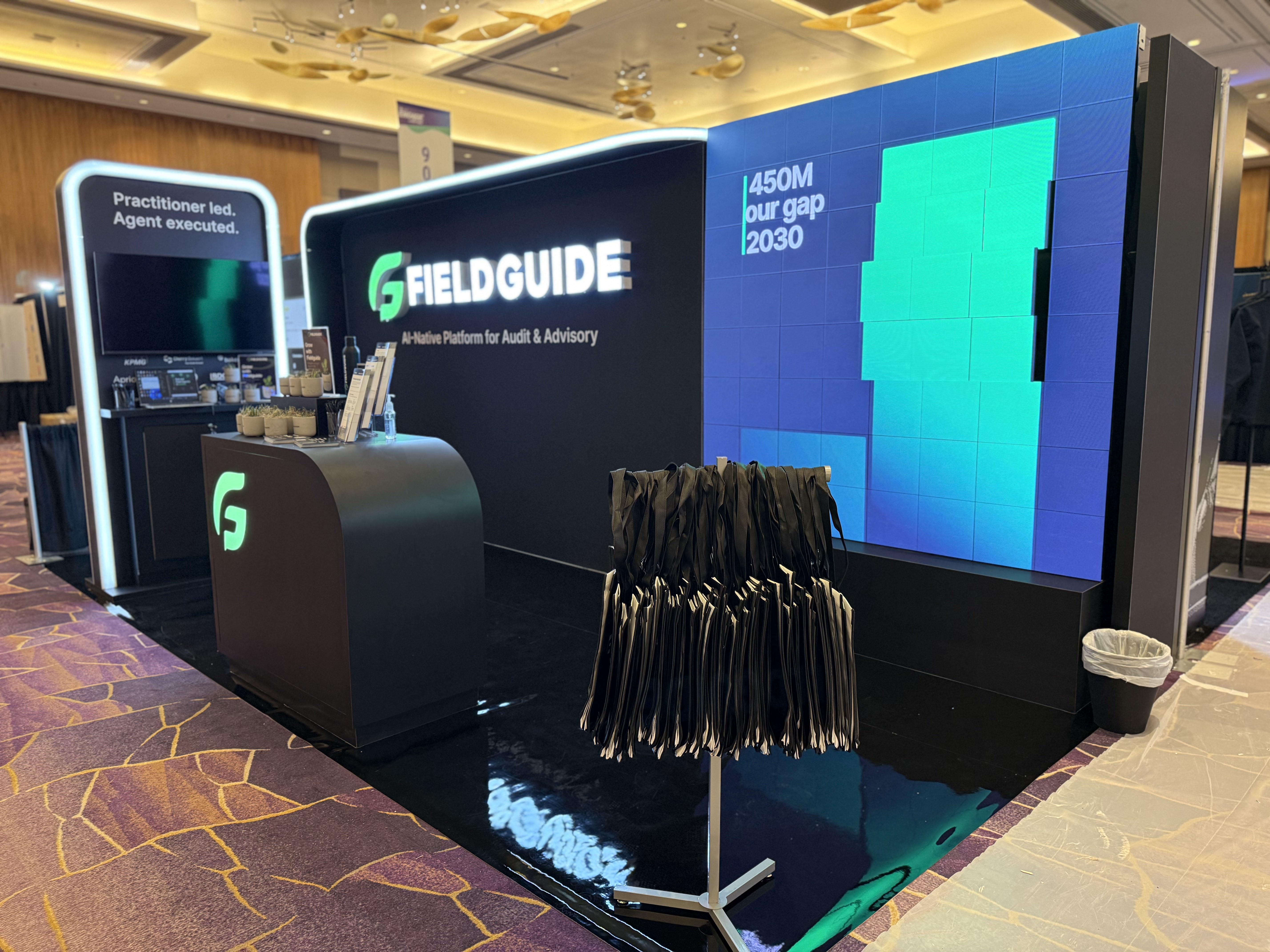 Branded trade show booth with large digital displays, custom counters, illuminated signage, and an open layout designed for visitor engagement.