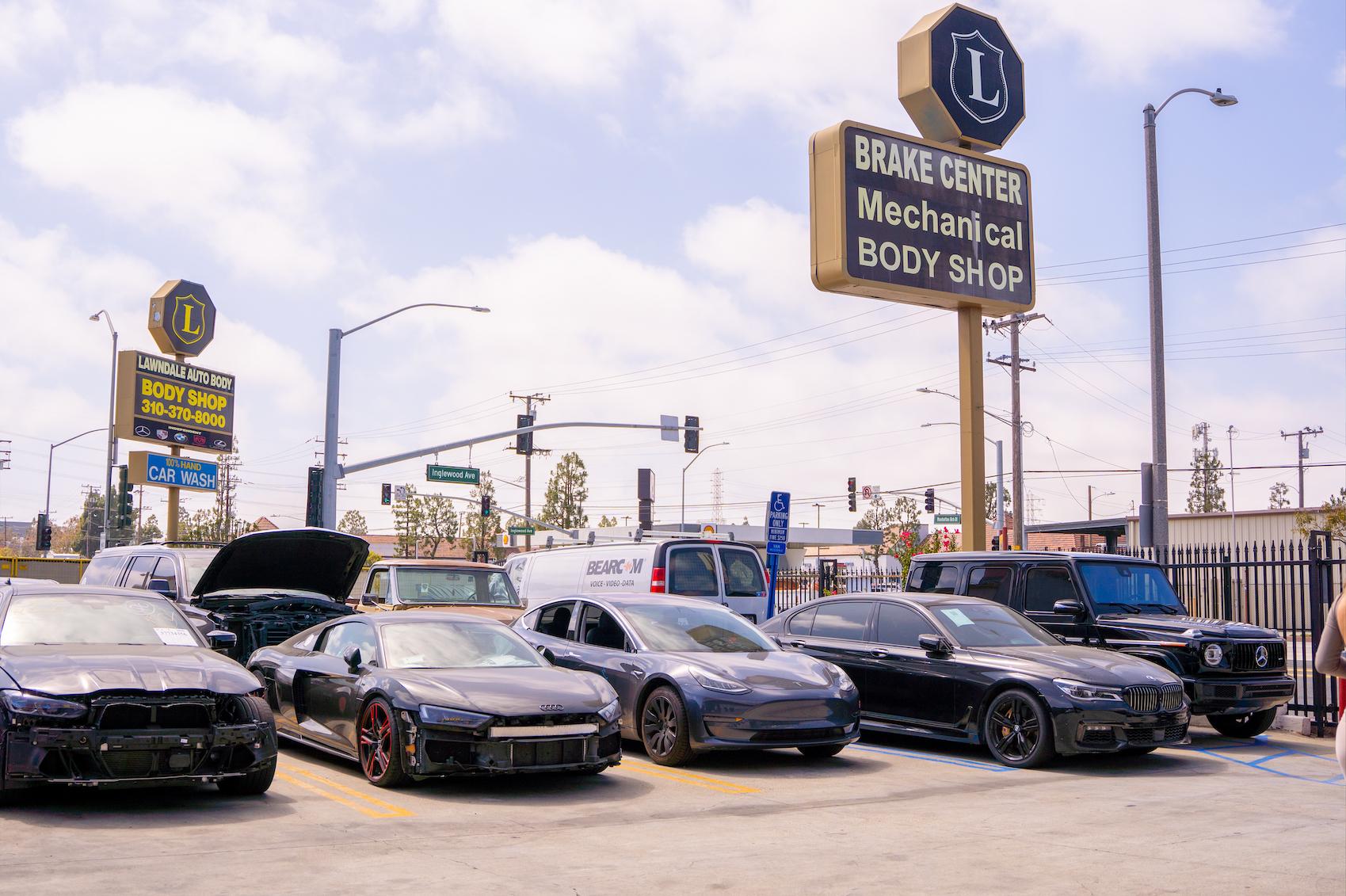 Line up of cars waiting for collision repair at LUXE Auto Body Shop