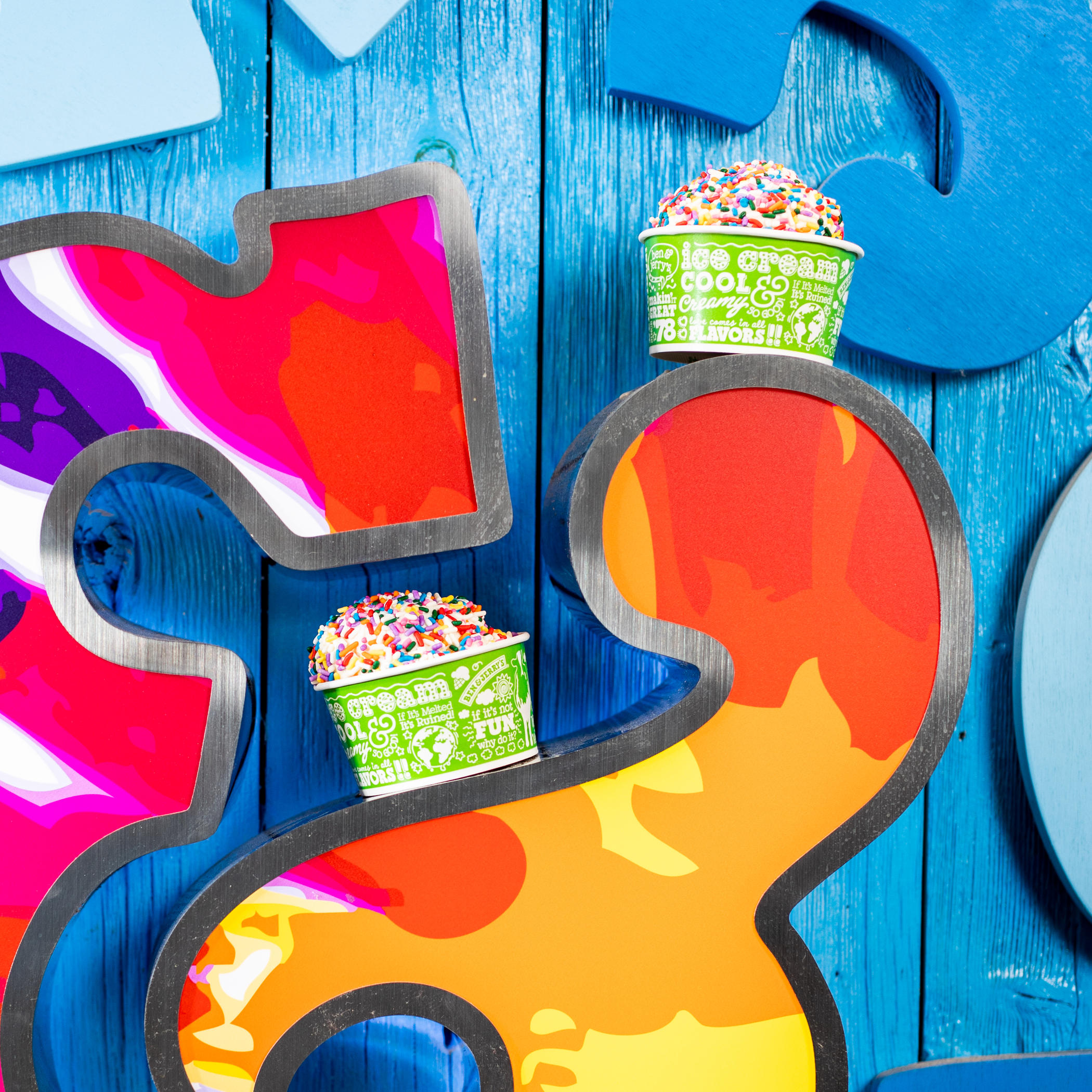 Two cups of ice cream with sprinkles on Ben & Jerry's Logo.