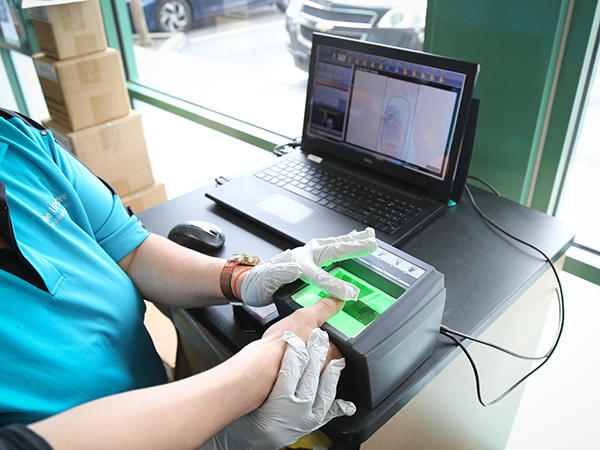 A The UPS Store associate scans the fingerprint of a customer's thumb