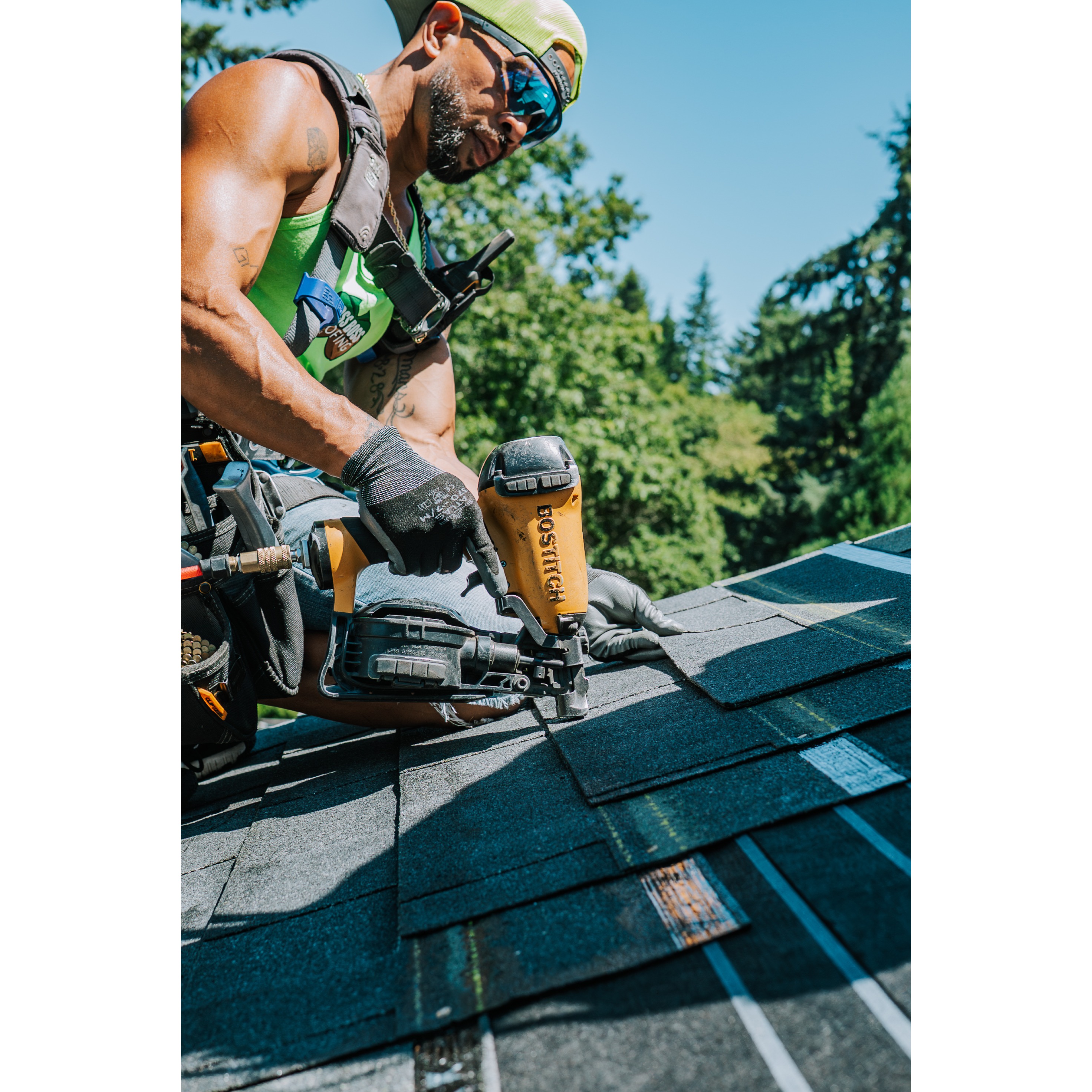 Close-up of a roofer using pneumatic roofing Nailer on asphalt shingles during roof installation. 