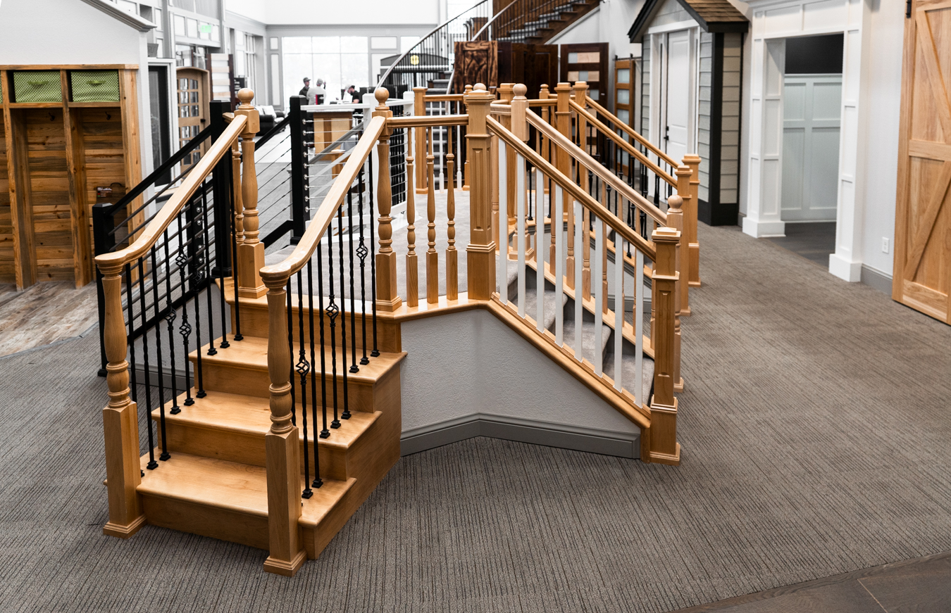 Builders FirstSource showroom with wooden staircases, black railings, and home interior displays.